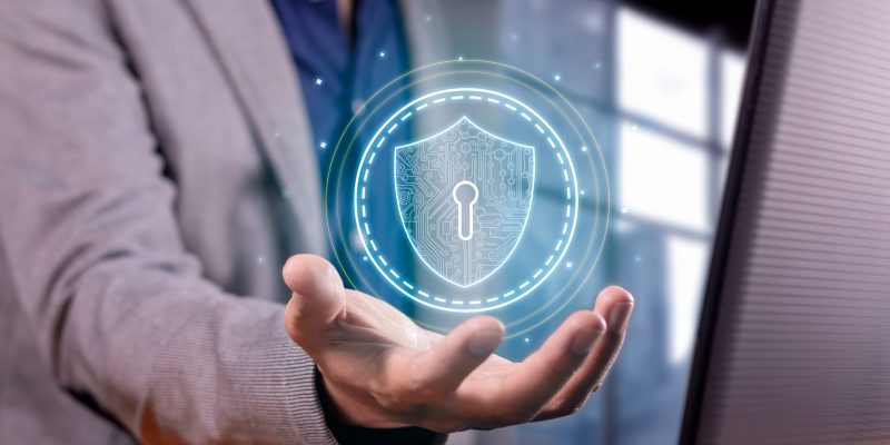 Symbolische Darstellung von Cybersicherheit – Geschäftsperson hält digitales Sicherheitssymbol zum Schutz sensibler Daten.